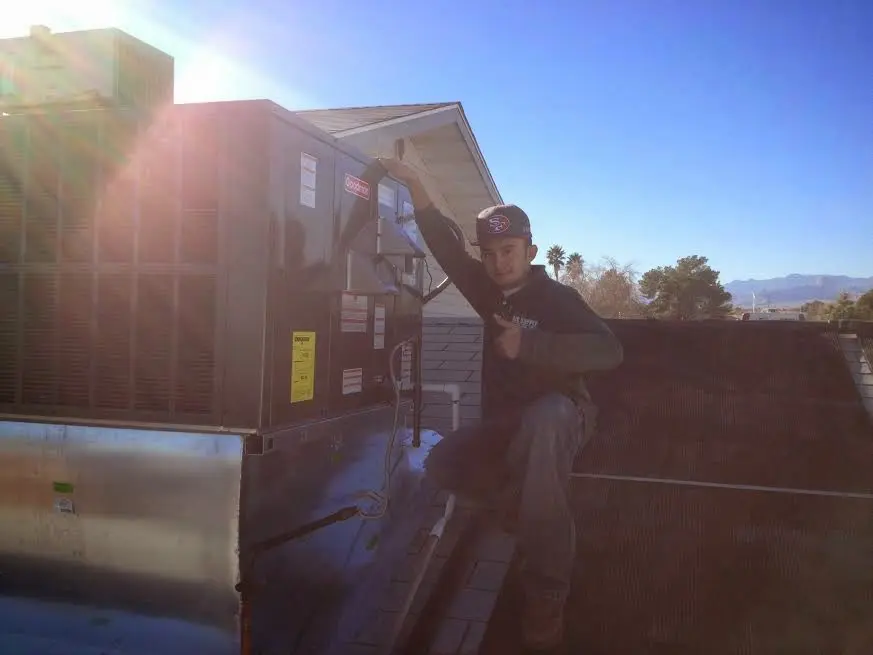 HVAC technician performing AC Tune-Up on a rooftop unit in Evans